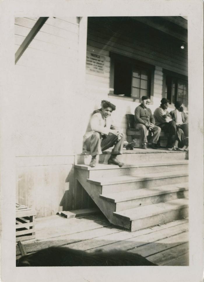 [Young man sitting on building steps]