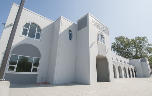 Exterior shot of a mosque with arched windows and decorative elements under a clear sky.