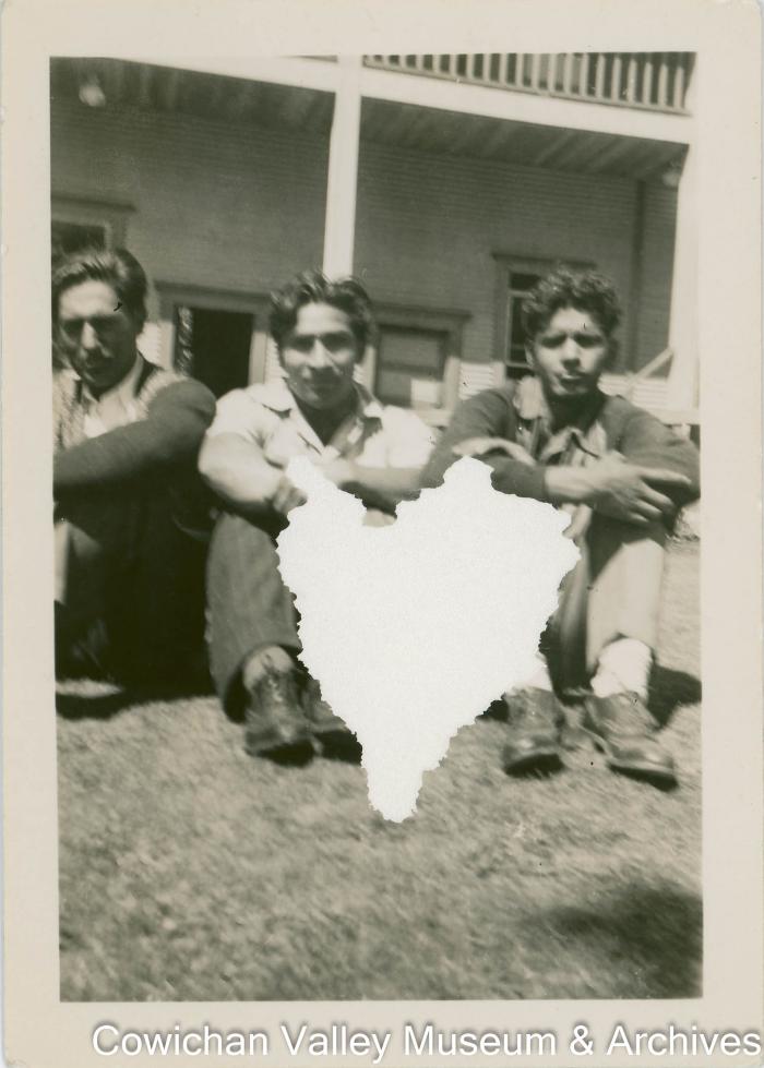 [Three men sitting in front of a building]