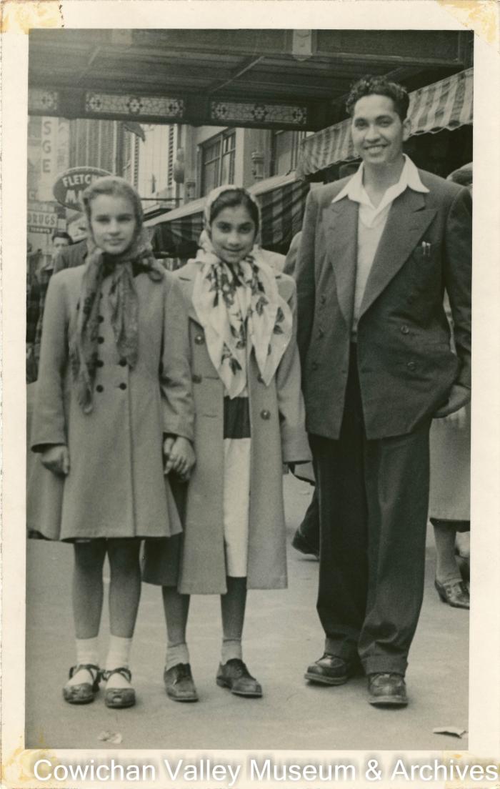 [A man and two young girls posing on a city street]