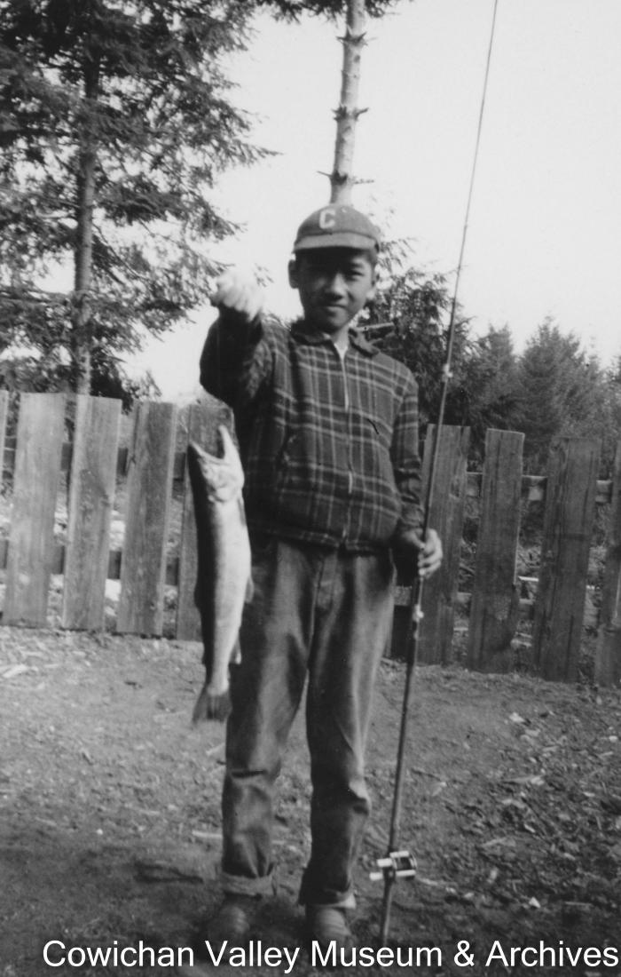 [A young boy holding a fishing rod and fish]