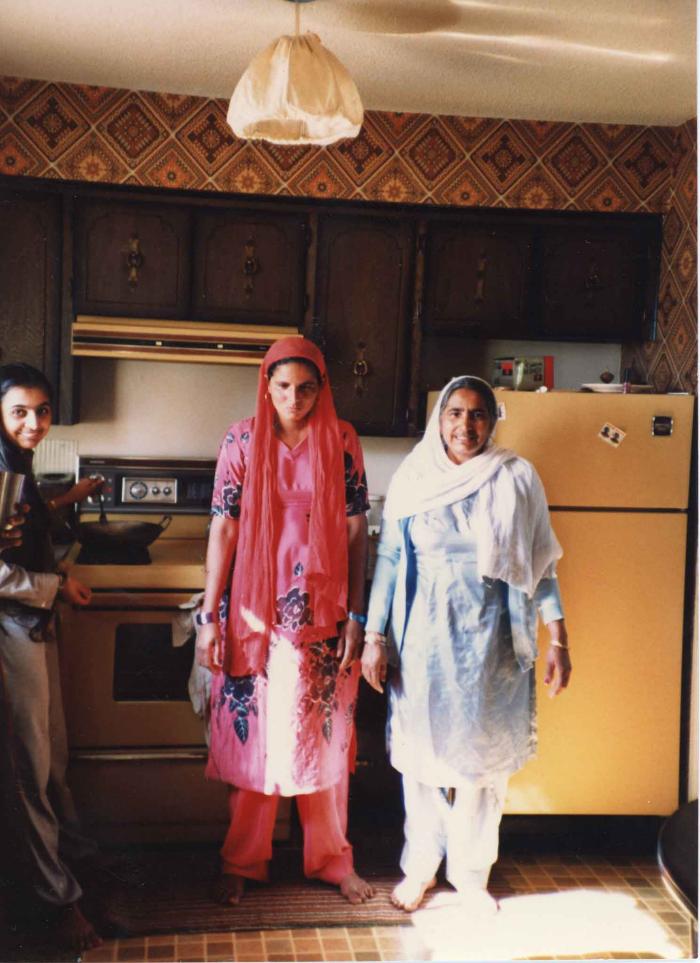 [Photo of Surjit Kaur in the kitchen with her family]