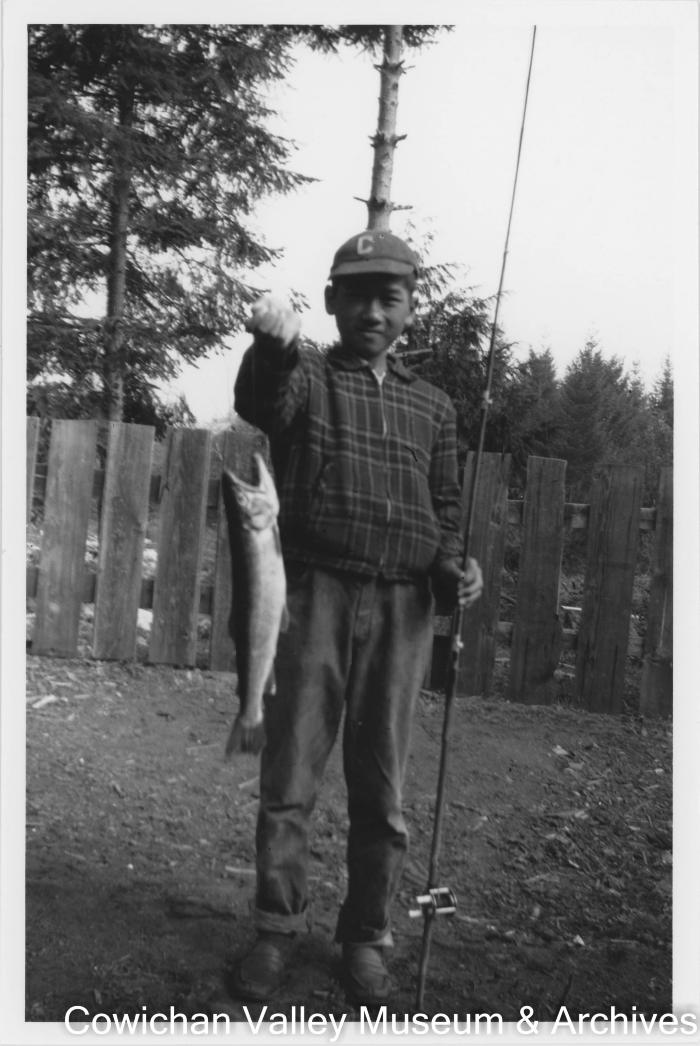 [A young boy holding a fishing rod and fish]