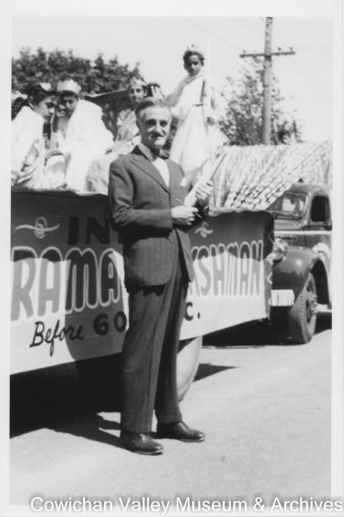 [A man in a suit standing next to a parade float]