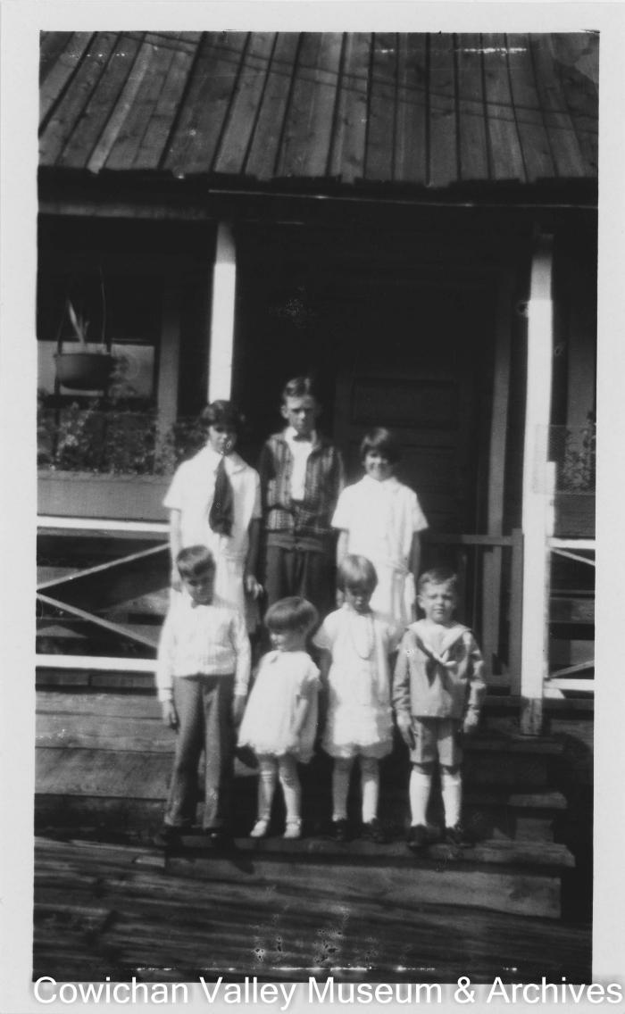 [Seven school children standing on front steps]