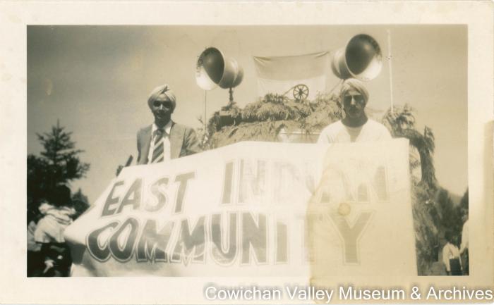 [Surdaran Singh and another man holding a parade float banner]