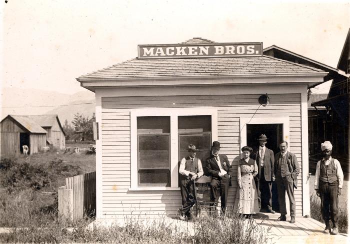 [Group photo in front of the Macken Brothers Lumber Yard building, Chilliwack, BC]