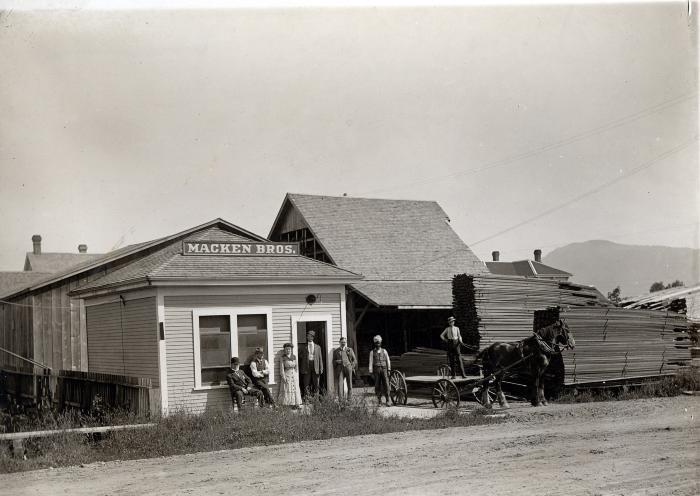 [Group photo in front of the Macken Brothers Lumber Yard building, Chilliwack, BC]
