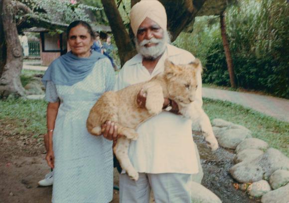 [Photo of Nirmal Singh holding a lion cub with Kishan Kaur]