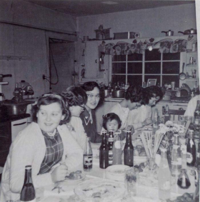 [Photo of a group of women and a child sitting at a dining table]