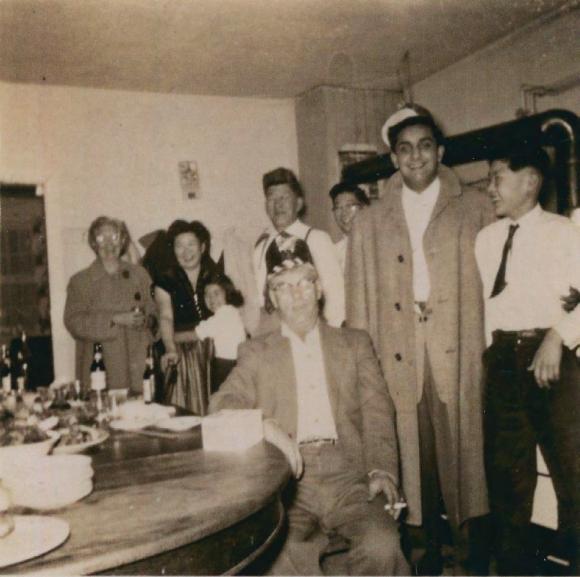 [Photo of a group of people gathered around a dining table]