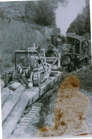 [Photo of a steam engine transporting logs and heavy duty equipment]