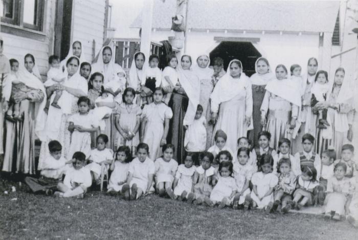 [Photo of a group of women and children standing in the backyard of Mayo Singh's house]