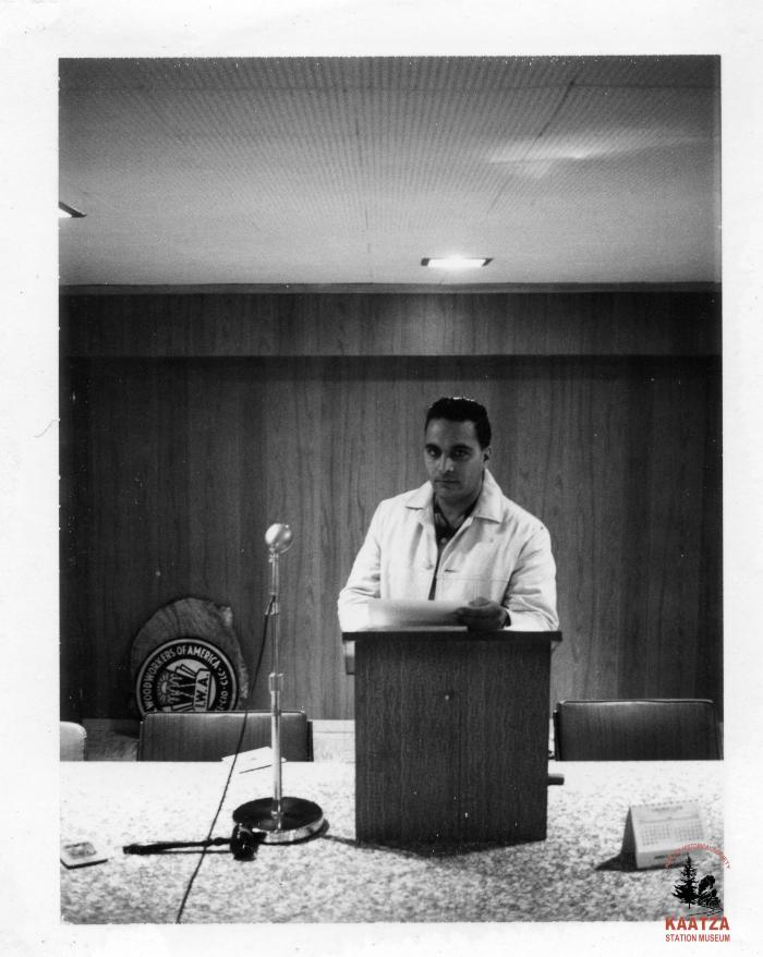 [Photo of IWA Local 1-80 Balloting Chairman Jager Gill standing behind a podium]