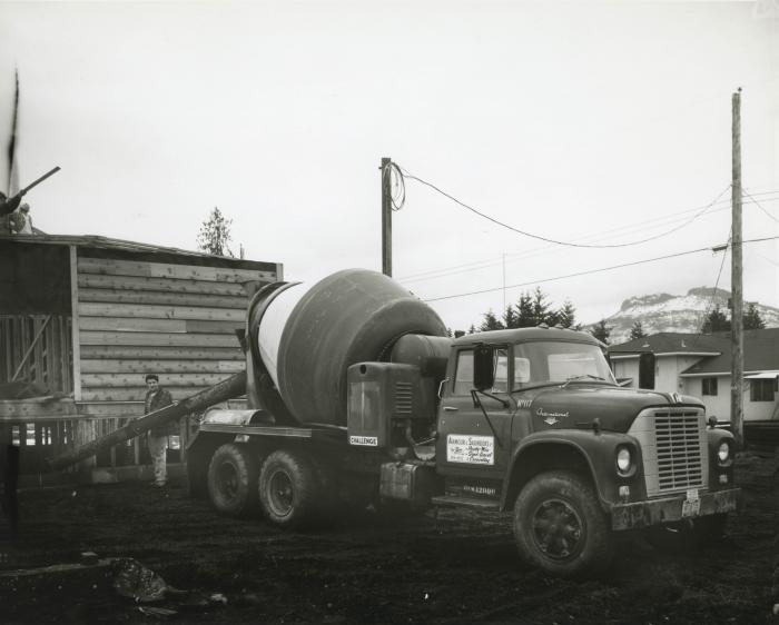 [Photo of an unidentified man and Armour & Saunders cement truck no. 117 at a house under construction]