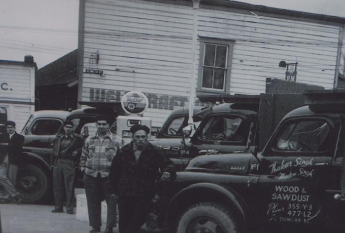 [Group photo of four transport workers and their hauling trucks at a fuelling station]