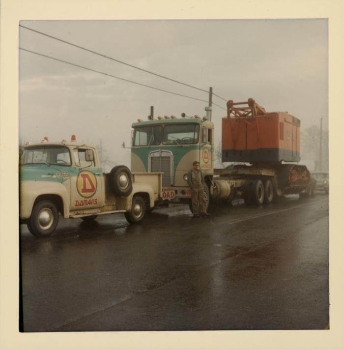 [Yellowed photo of a Doman Industries transport worker with transport trucks no. 65 and no. 140]