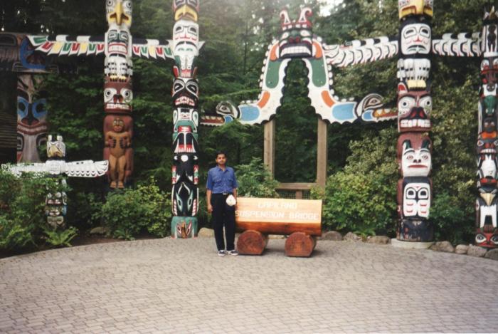 [Photo of Subbu Govindarajapuram in front of the totem poles at the Capilano Suspension Bridge Park, B.C.]
