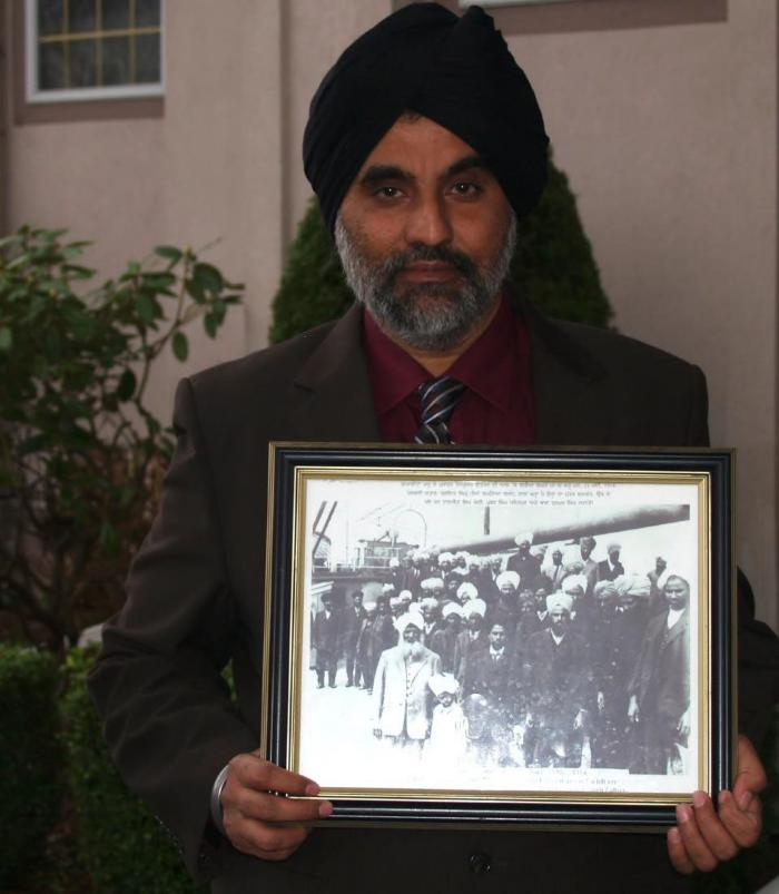 [Rajwant Singh Toor holding photograph of Komagata Maru passengers, including his grandfather, Puran Singh Johal]