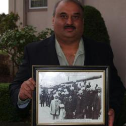 [Jaswinder Singh Toor holding photograph of Komagata Maru passengers, including his grandfather, Puran Singh Johal]