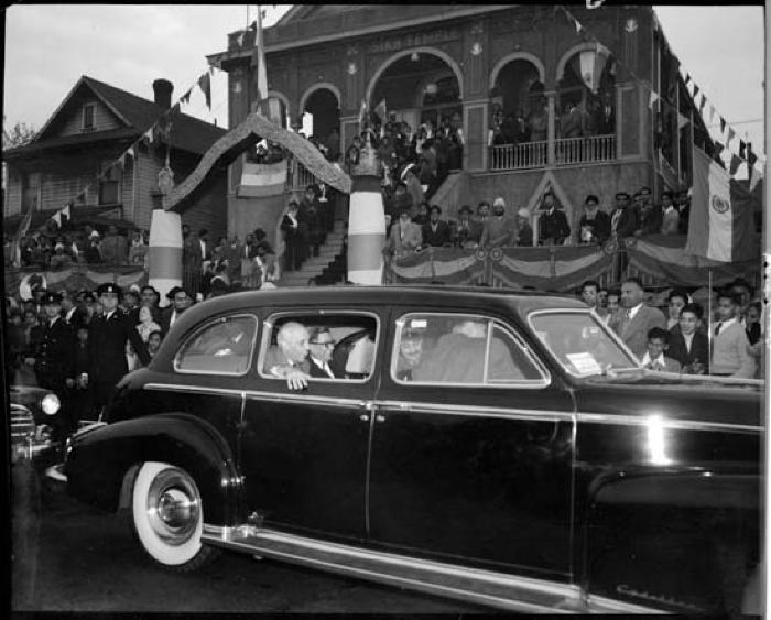 Nehru in the rear seat of a car with the Sikh temple in the background