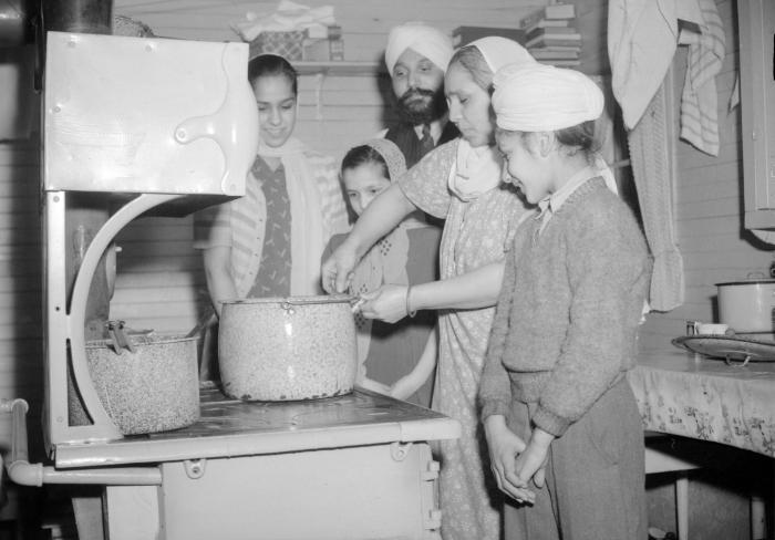 [Sikh family standing around a stove]
