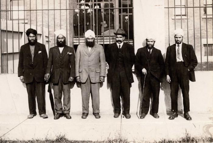 [Group photo of Husain Rahim and five unidentified individuals in front of the Immigrational Hall in Victoria, BC]