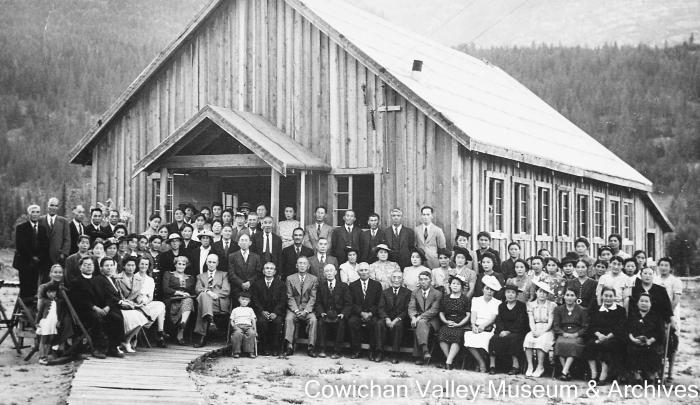 [Unidentified group of people in front of large wood building]