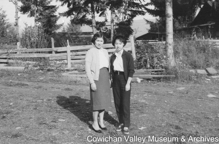 [Two unidentified women standing on a dirt road]