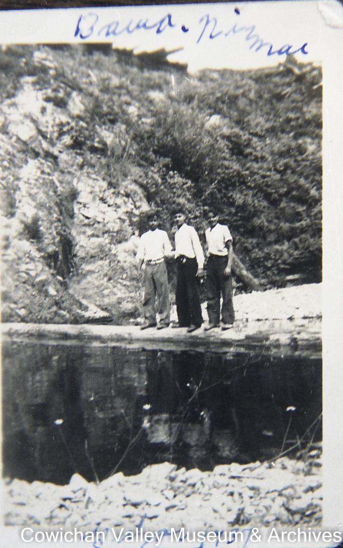 [Three unidentified young men on the bank of a stream]