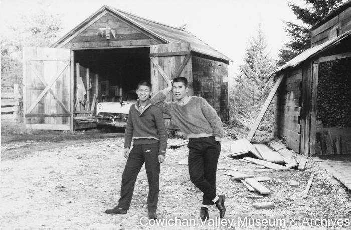 [Two unidentified men standing in front of garage]