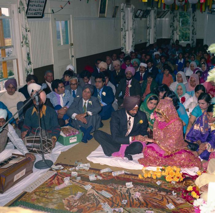 [Group photo of Balbir Khangura and Baljit Gill with wedding guests in ring ceremony]
