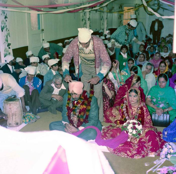 [Group photo of Inderjit Cheema and unidentified bride with wedding guests]