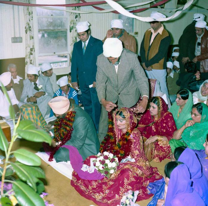 [Group photo of Inderjit Cheema and unidentified bride with wedding guests]