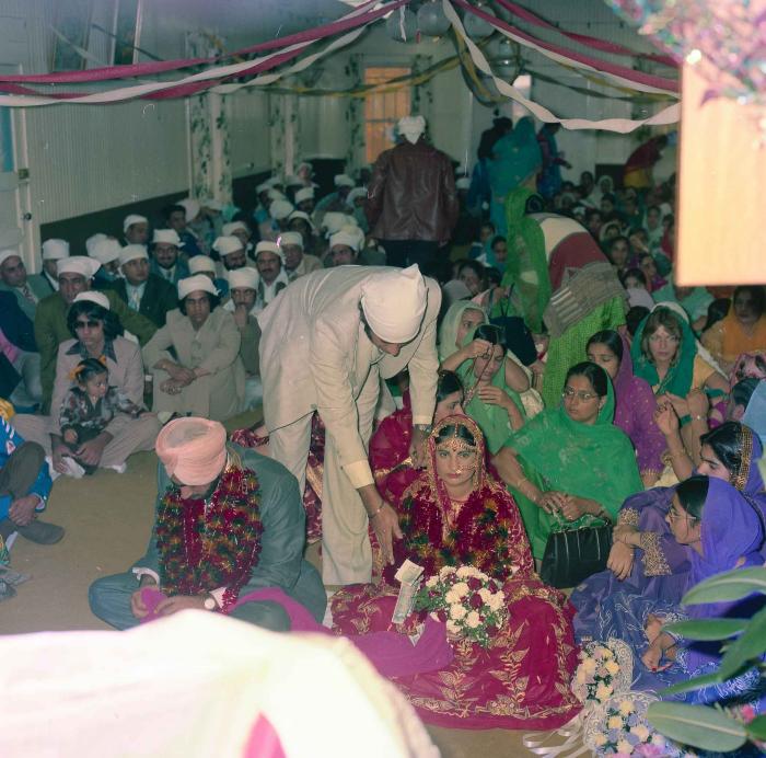 [Group photo of Inderjit Cheema and unidentified bride with wedding guests]