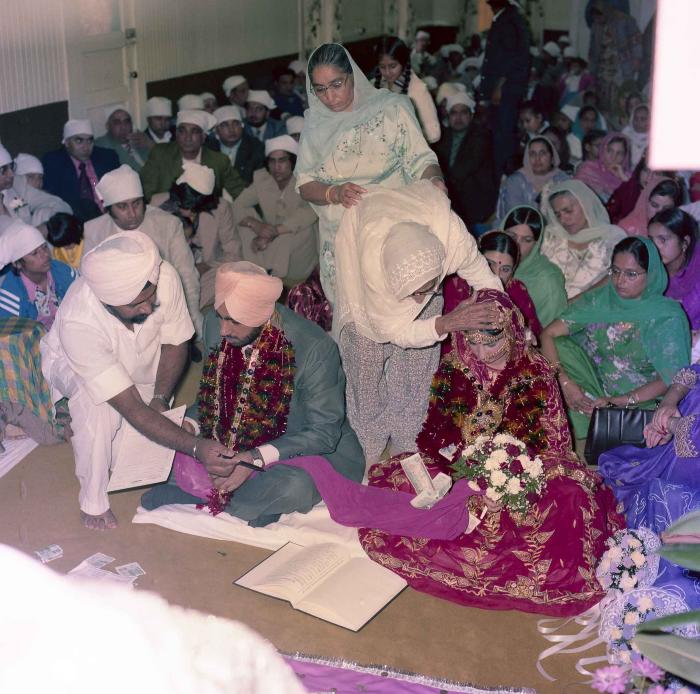 [Group photo of Inderjit Cheema and unidentified bride with wedding guests]