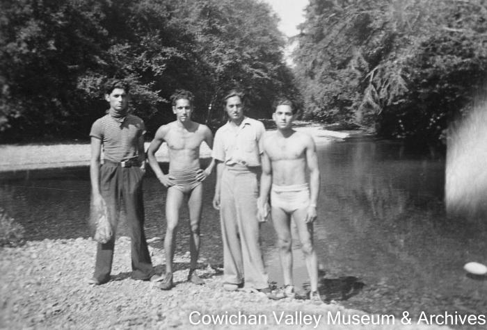 [Four unidentified men standing near the river]