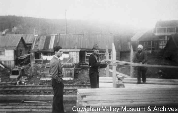 [Three unidentified men stacking lumber]
