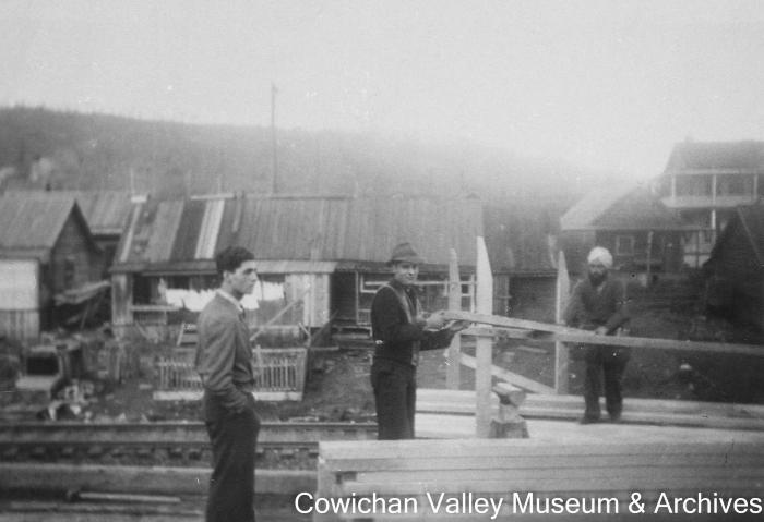 [Three unidentified men construting a wood fence]