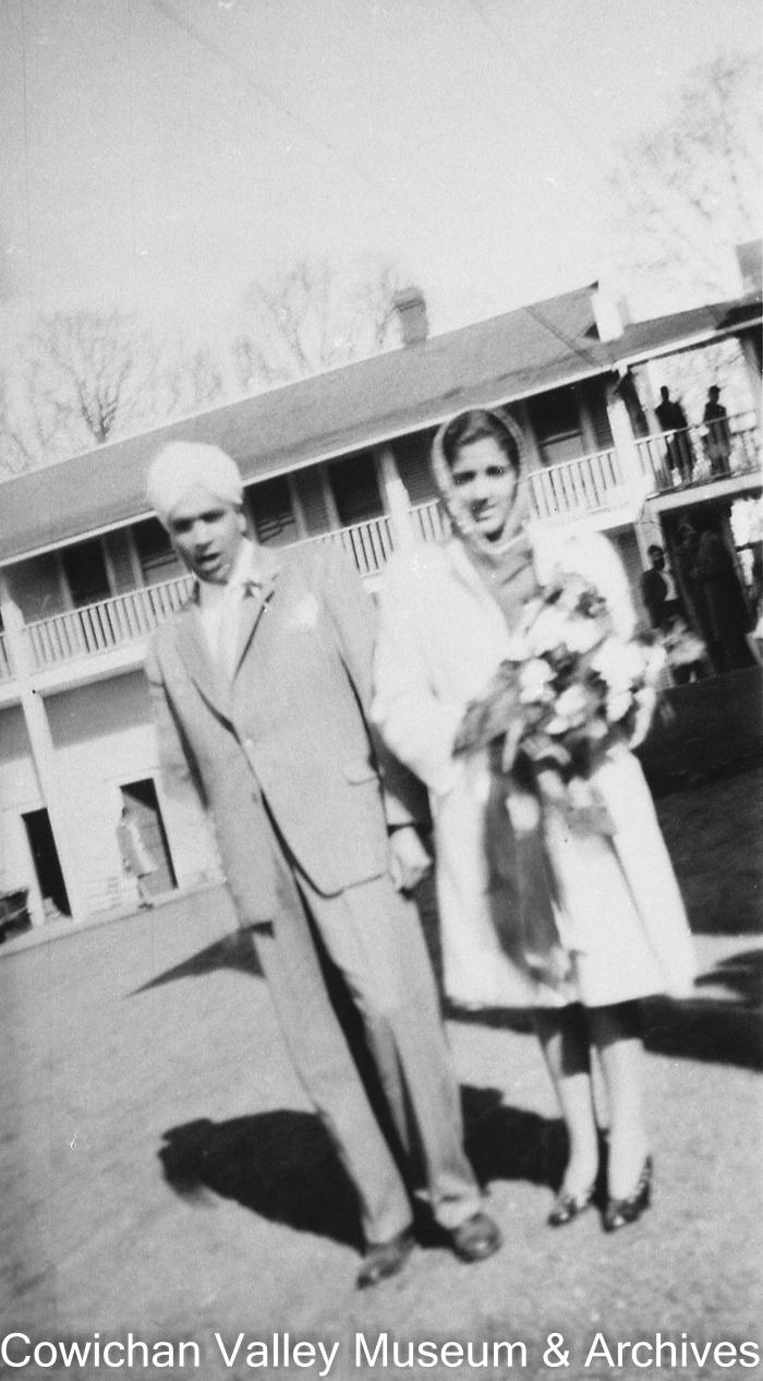 [An unidentified woman and an unidentified man in front of a two story building]