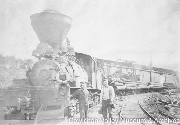 [Three unidentified men standing infront of locomotive]